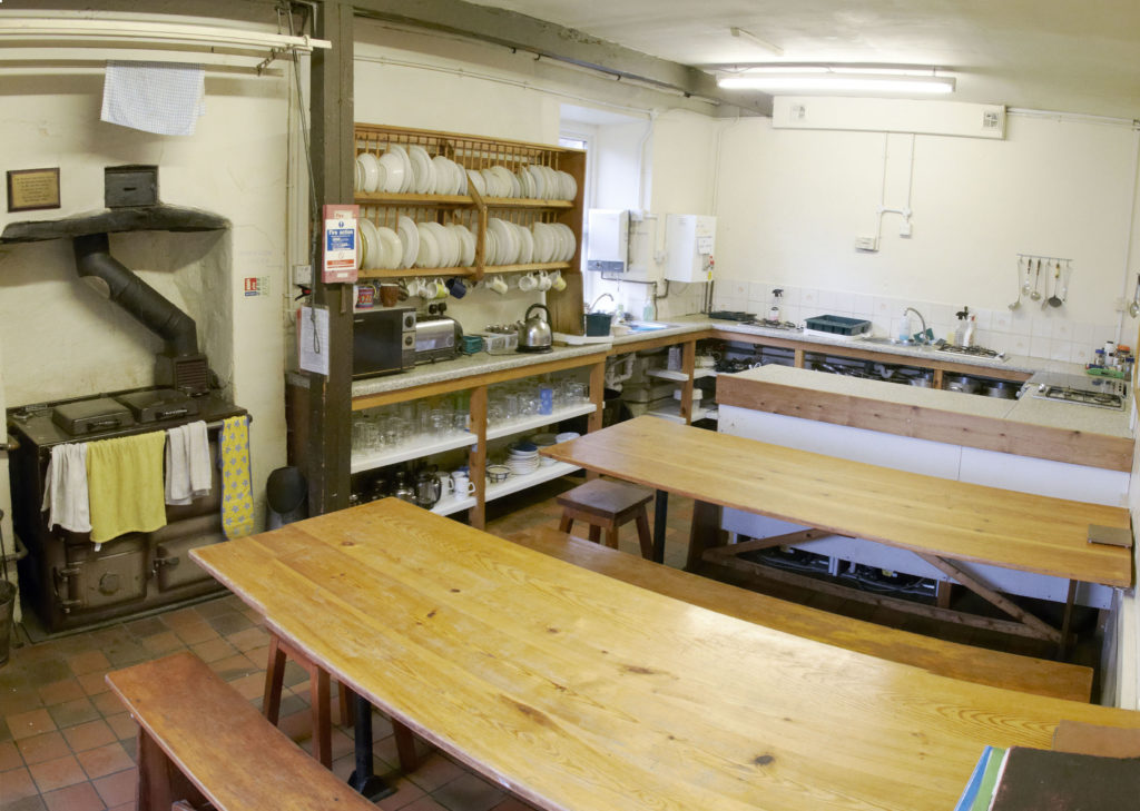 View of the rayburn, gas hobs, sinks, benches and crockery in the kitchen at Blaen-y-Nant